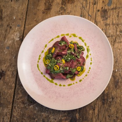 Dünn aufgeschnittenes Fleisch mit Kräutersauce und gelben Chiliringen